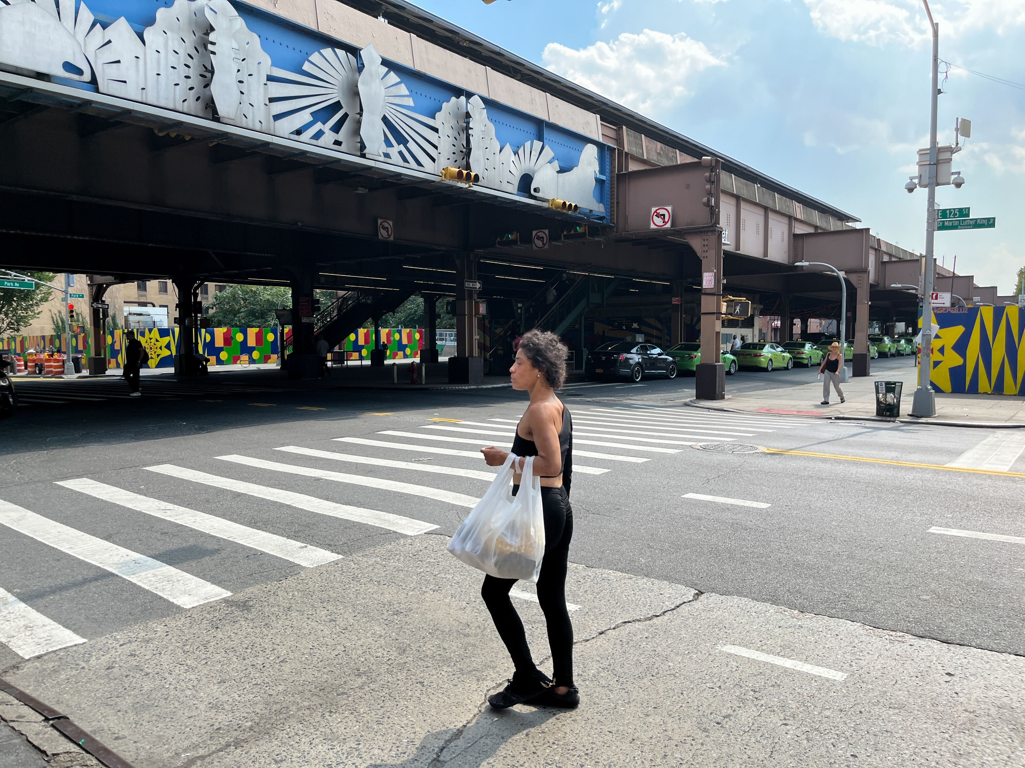A woman walks across Lexington Avenue at 125th Street.