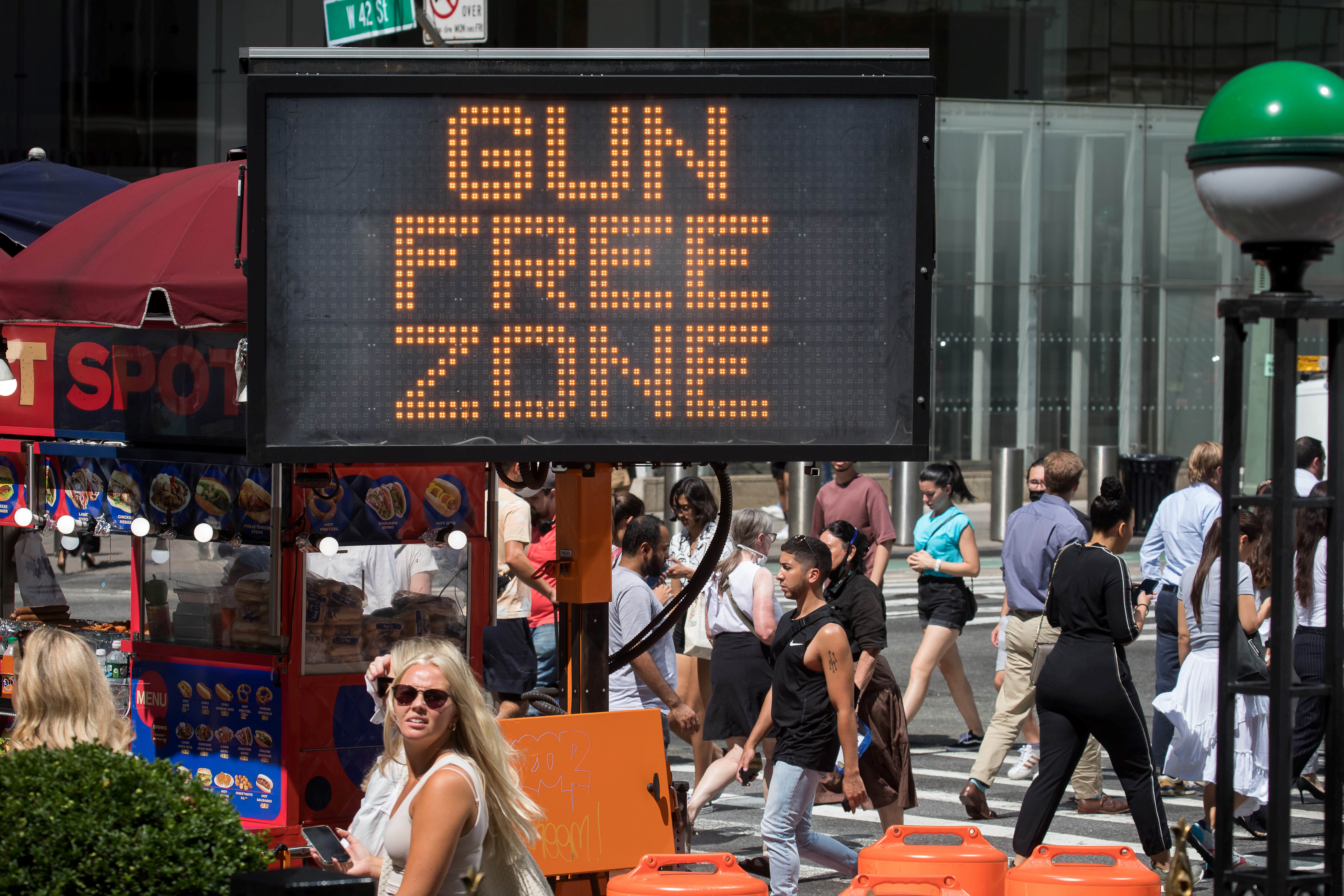 Passersby walk past a gun-free zone signboard near Times Square. New York State started to prohibit concealed carry of weapons in designated sensitive areas, including Times Square, bars, libraries, schools, government buildings and hospitals, across the state after the U.S. Supreme Court struck down the state's century-old concealed carry weapons law.
