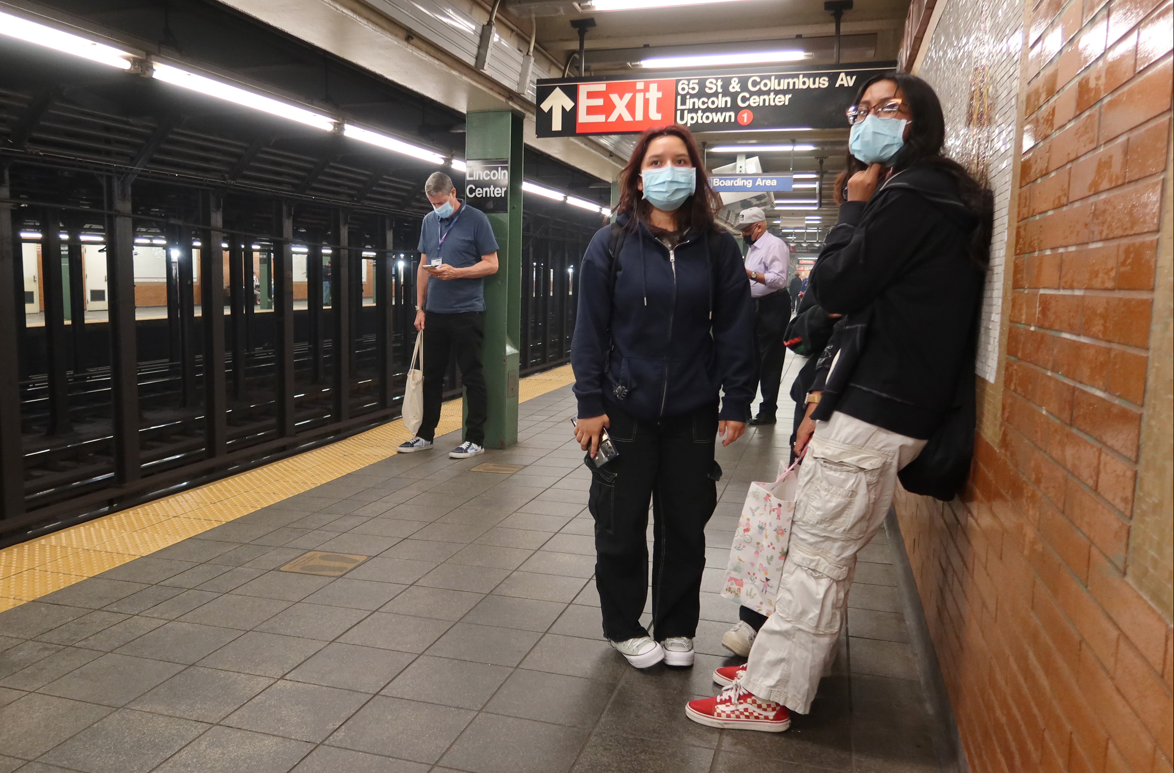 People wear masks as they wait for a subway train.