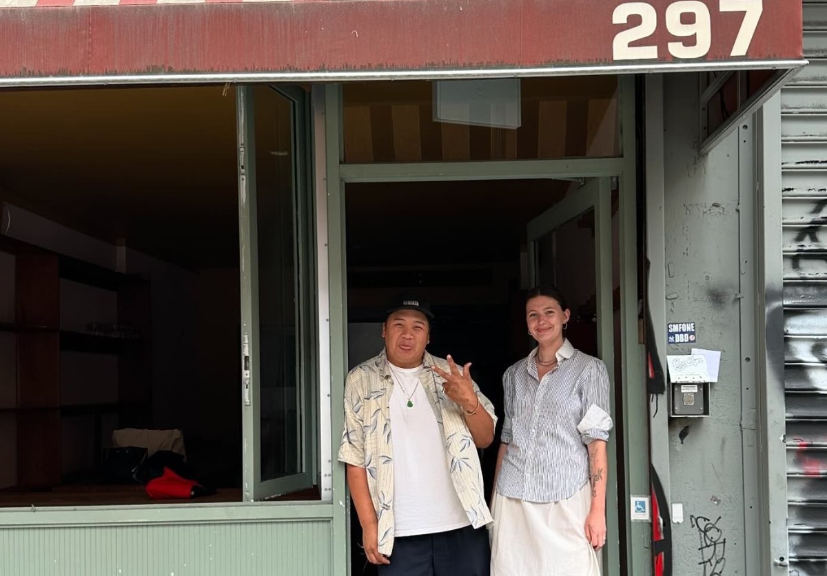 Two people stand in front of a restaurant door.