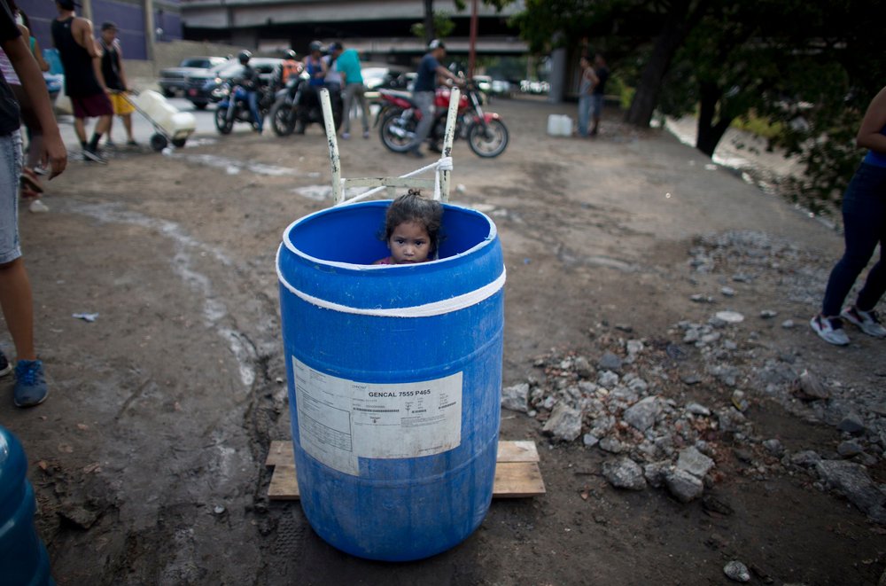018f61e8810150689h-jpg.jpeg A little girl stands inside a plastic barrel while her family waits to collect water from an open pipe above the Guaire River, during rolling blackouts which affect the water pumps in people's homes, offices and stores, in Caracas, Venezuela.<br/>(Ariana Cubillos/AP/Shutterstock)