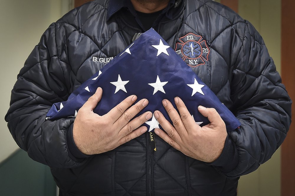 031a30b0833328204932_21723bfe2a_b-jpg.jpeg Benny Guzman of FDNY Station 20 in the Bronx holds a flag for a fallen EMT after a fatal incident during an evening shift (NYC Mayor's Office)