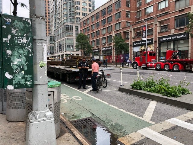 An NYPD officer tickets a cyclist on 6th Avenue just north of West 24th Street, where bike messenger Robyn Hightman was killed by a hit and run truck driver last month.