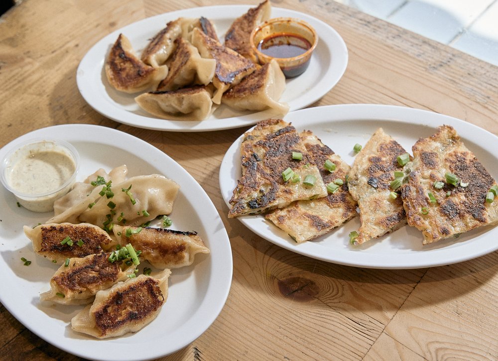 White plates filled with dumplings and savory pancakes on a table.