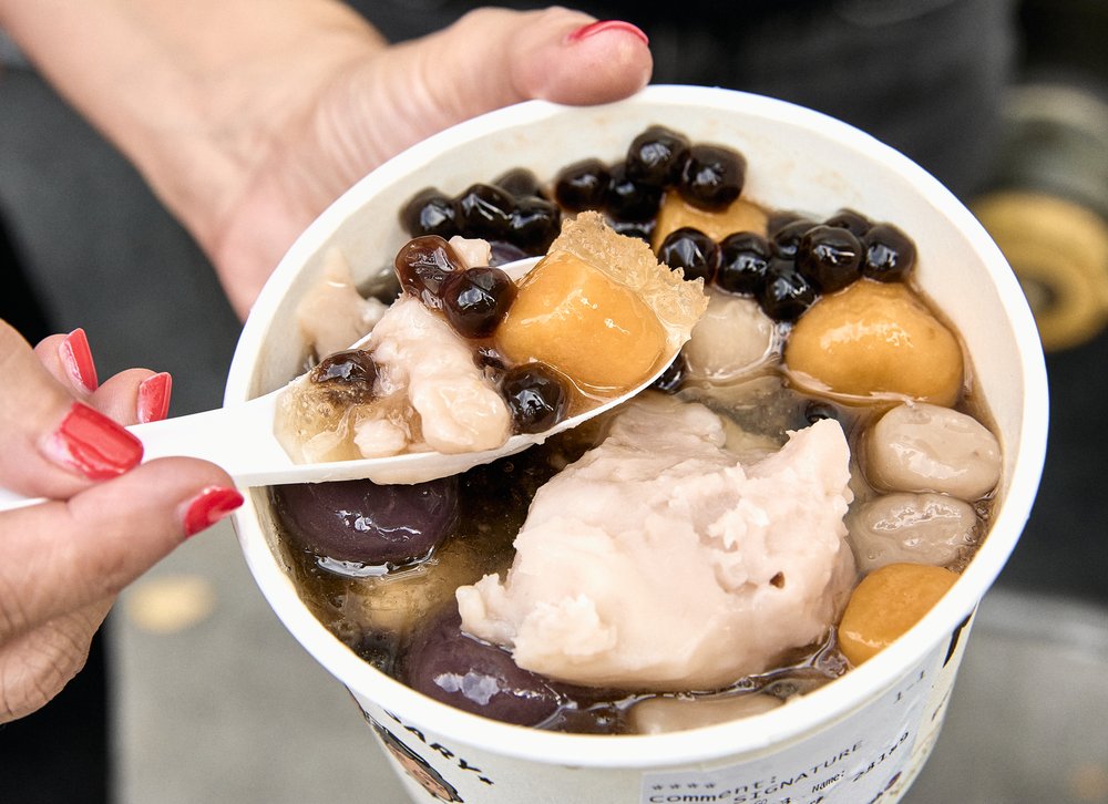 A treat in a cup with small balls and fruit.