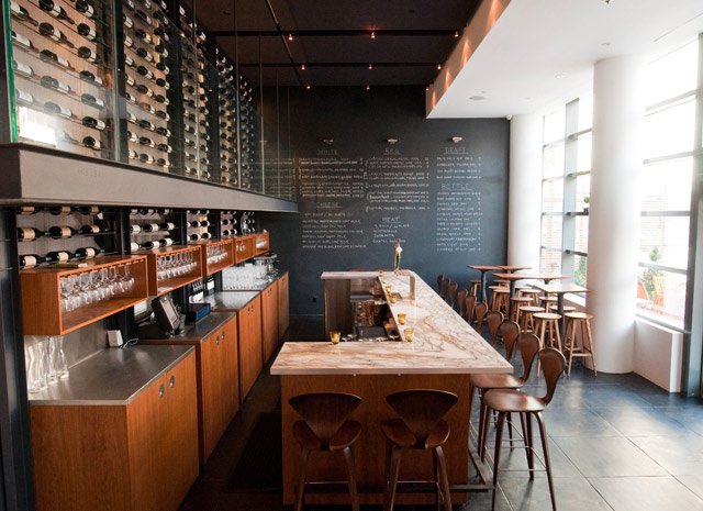 101709Ardesia3sm.jpg Ardesia: Hell's Kitchen's latest wine bar is attempting to bridge the gap between the neighborhood's gritty past and glitzy future. Run by Mandy Oser of Le Bernardin, Ardesia offers wine and some upscale snacks at prices bordering on affordable. Their 50-seat interior features slate floors and a white marble bar in contrast with cozy, plush couches for lounging. The main draw of the place, however, is the two-story wine wall, "meant to evoke the fire escapes of the area's old tenement buildings," that the bartenders must scale to retrieve your selection. If only all of our fire escapes were filled with wine! Most glasses are under $16, with a wide range of regions and styles to choose from. A menu of homemade cheeses and charcuterie complements the wine selection, and heavier plates include house-cured duck banh mi and homemade pretzels served with cheese fondue. 510 West 52nd St, 212-247-9191