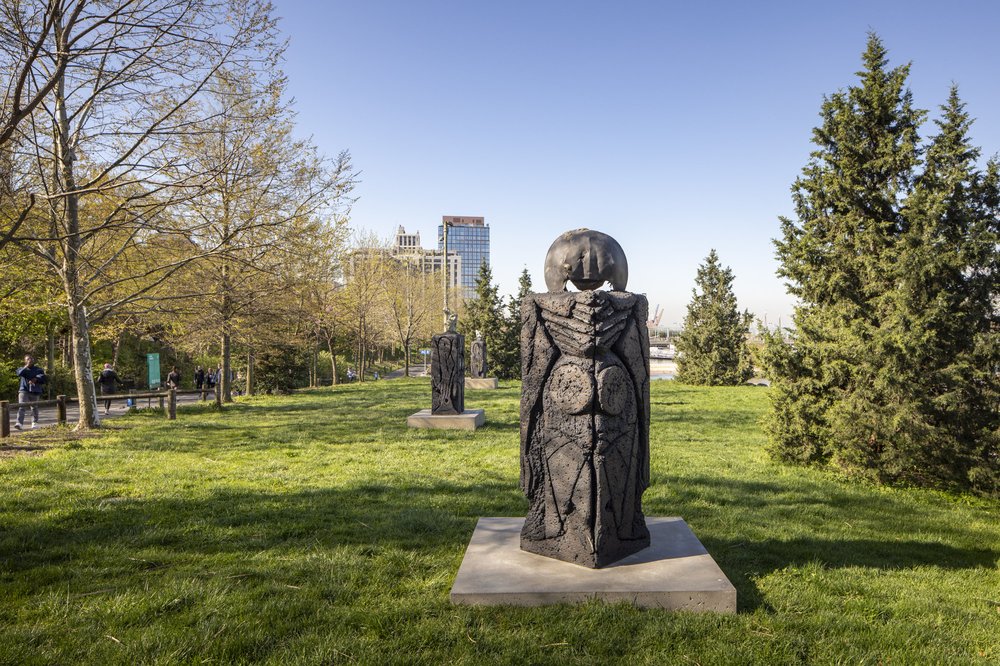 A bronze statue on a green field in a park.