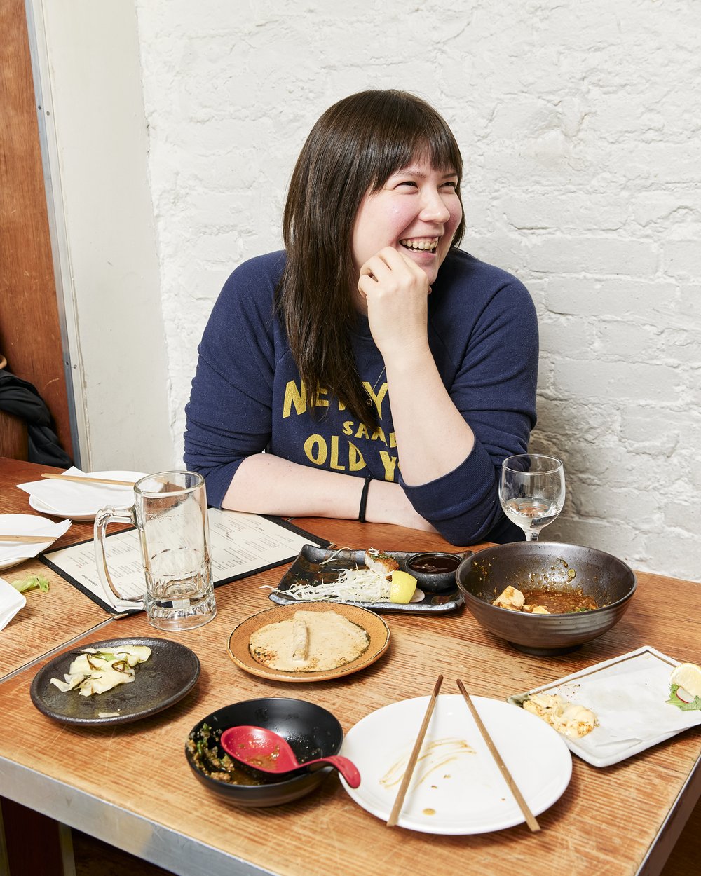 A woman sits at a table in a restaurant.