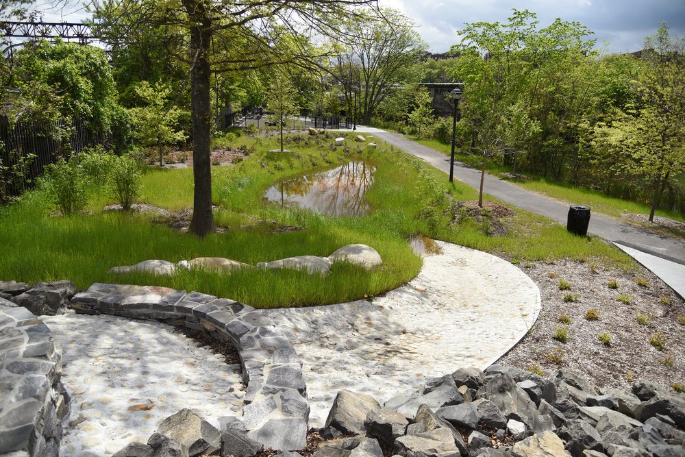 A stone weir and channel, designed to slowly release water down into a new rainwater garden. These pieces of green infrastructure are interwoven into the parks paths and public spaces.