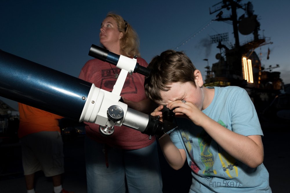 A child looks into a telescope.