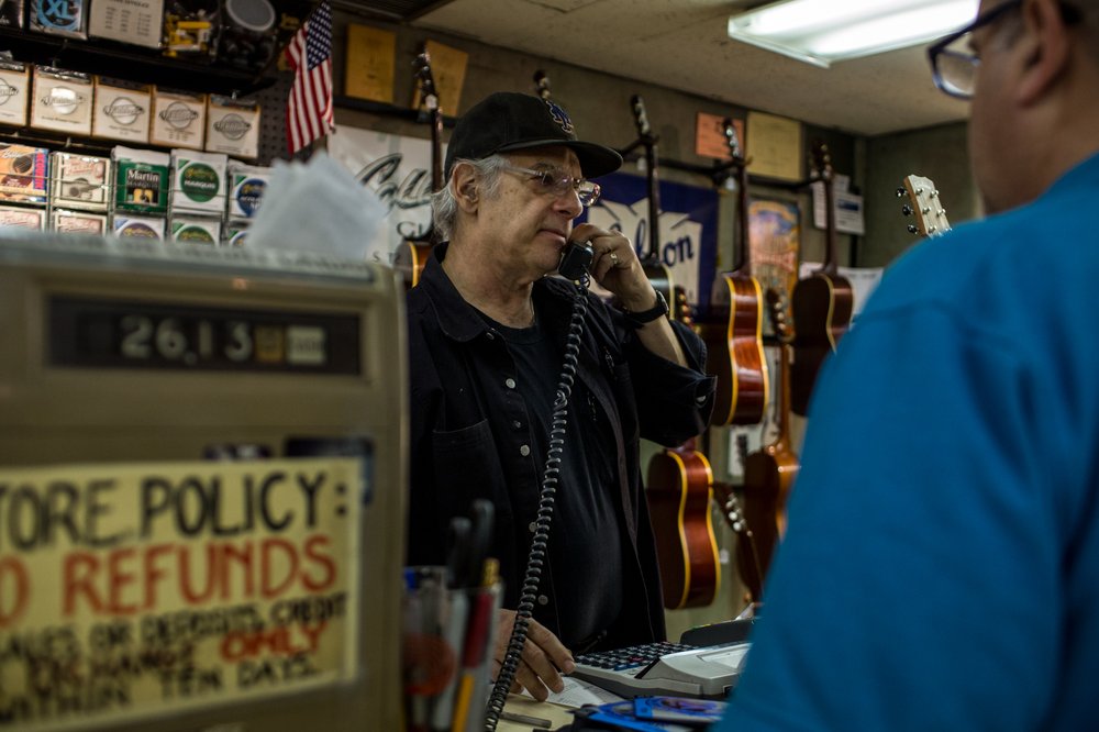 1784b4b71100317mattumanovguitars-5-jpg.jpeg Owner Matt Umanov juggles customers Monday at his store, which will close later this year.