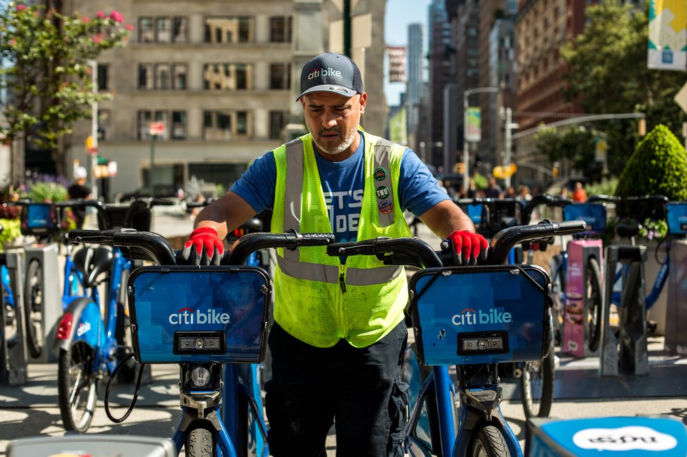18591eea2080917newsafestreetsflatiron-jpg.jpeg Citi Bike Senior Driver Ed Avilez removes two bikes from the racks at Broadway and West 24th Street in Flatiron, Manhattan. The Citi Bike docking station will soon move across 24th Street to free up pedestrian space.</br>