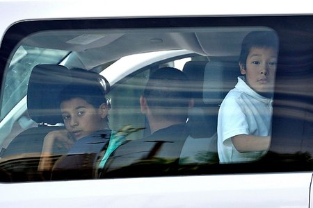 Migrant children look out a van window as they arrive at Lutheran Social Services in Phoenix.