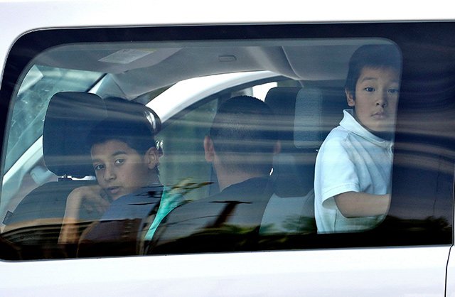 Migrant children look out a van window as they arrive at Lutheran Social Services in Phoenix.
