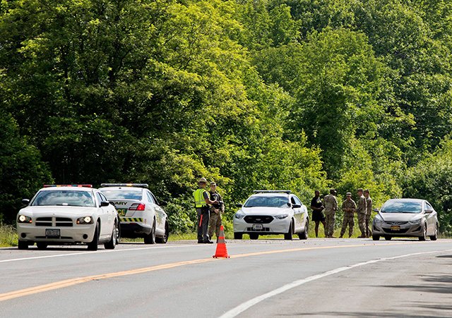 Military police and civilian first responders stand along Route 293 in response to a rollover of an armored personnel vehicle in which at least one person was killed, in Cornwall, N.Y.