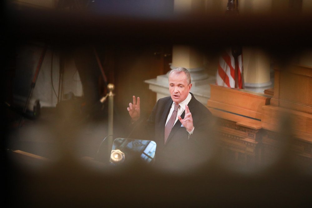 Governor Phil Murphy addressing the NJ Legislature in February 2020, as seen through the railings in the state house