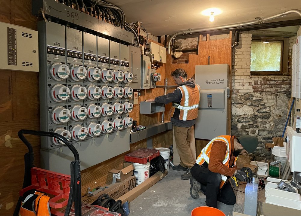 A team from Sunkeeper Solar, a Brooklyn-based solar installation company, finishes connecting new rooftop solar panels to a building’s energy supply.