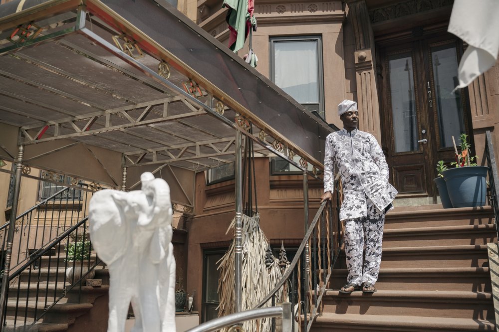 A person stands on the steps of a brownstone.