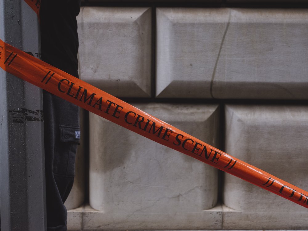 Orange crime scene tape that reads "Climate Crime Scene."