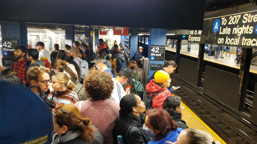 People pack onto platform of the A train at the 42nd Street subway station as delays and service changes strand commuters.