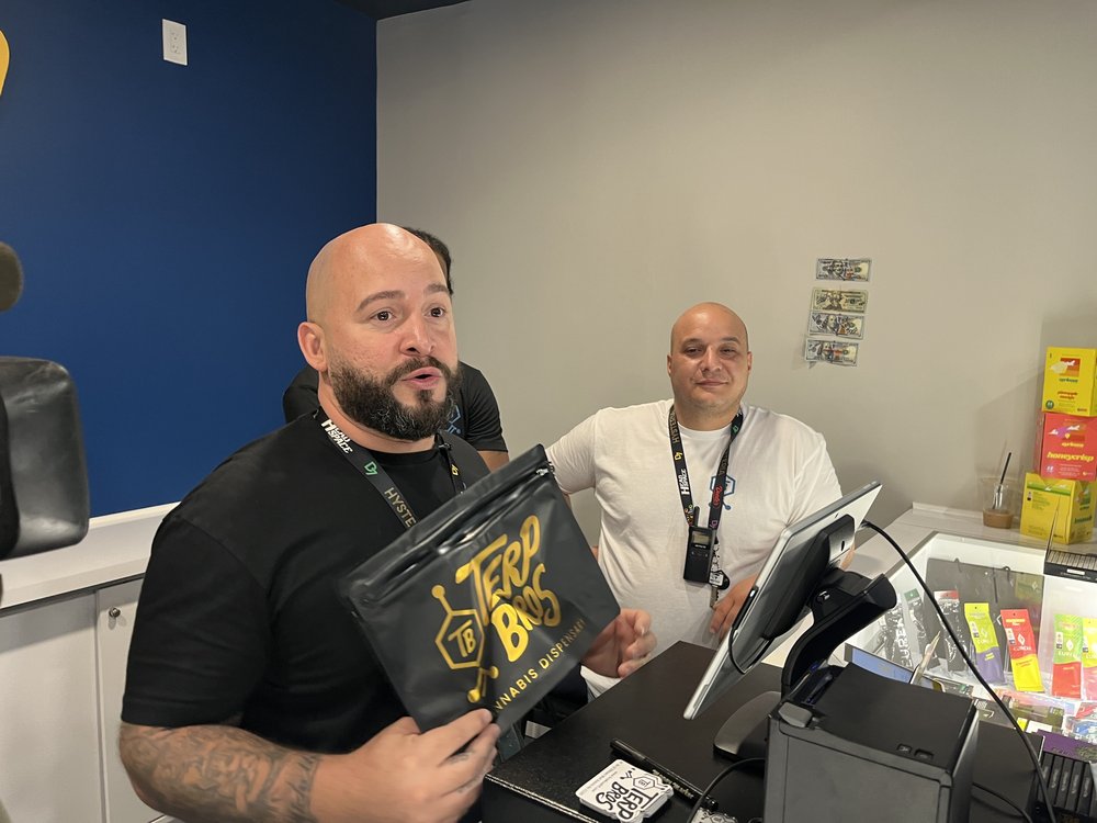 Jeremy Rivera holds up a bag of cannabis goods that were purchased on opening day at his shop Terp Bros.