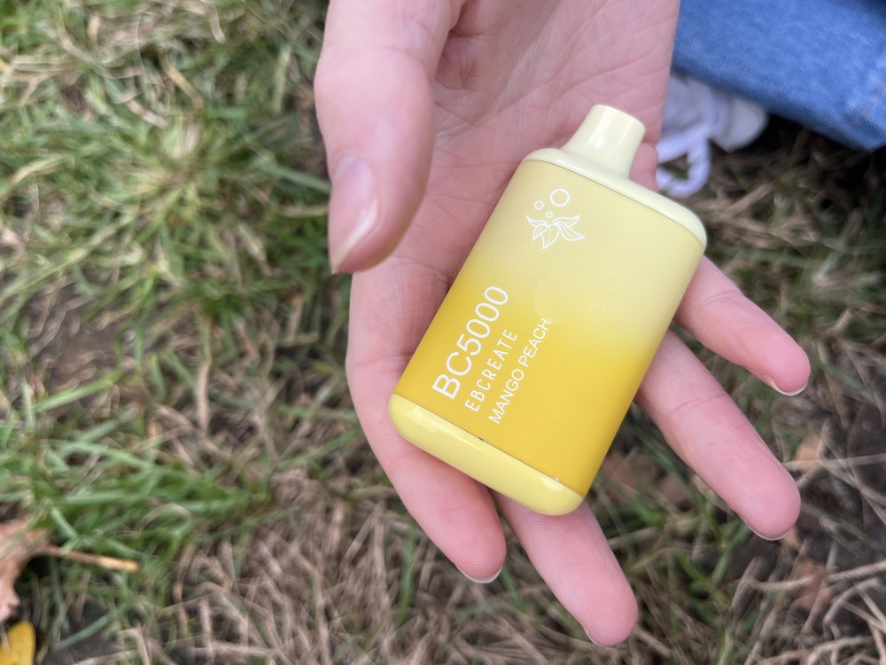 Jasmine McClure holds a peach mango flavored vape in Washington Square Park.