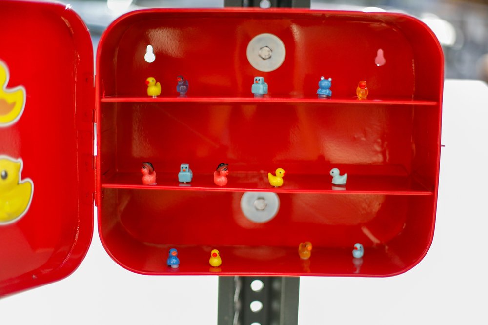Tiny duck figurines on shelves in a red box.