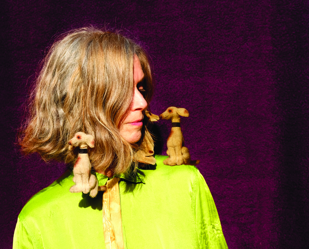 A woman in a bright green blouse with toy dogs on her shoulders