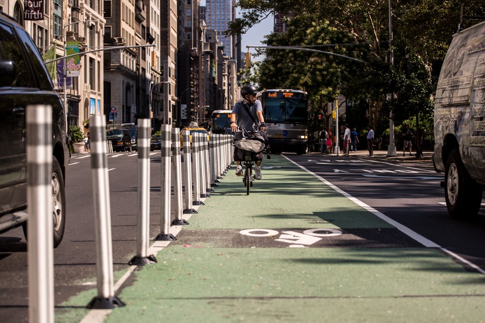 2d559c642080917newsafestreetsflatiron-5-jpg.jpeg A man bikes down a newly-installed protected bike lane on 5th Avenue between West 25th and 24th Streets in Flatiron, Manhattan. The lane was given additional protection as part of the DOT's new Shared Streets redesign.</br>