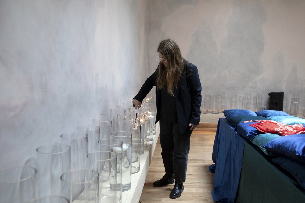 A woman lights candles inside an expansive room.