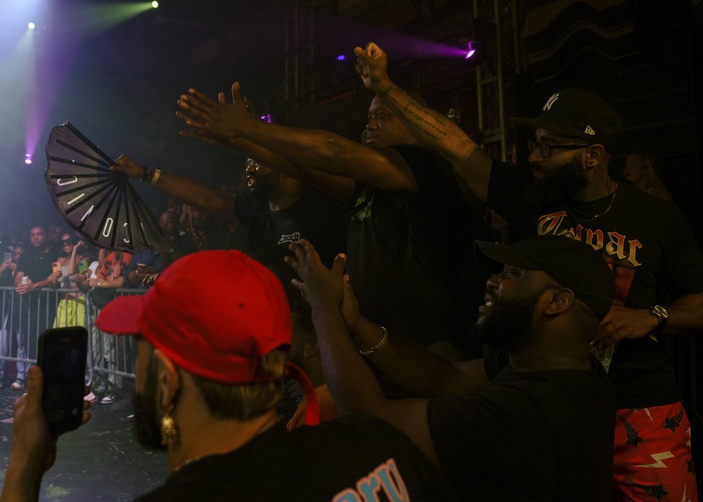 A crowd of people cheer on dancers with snaps and claps.