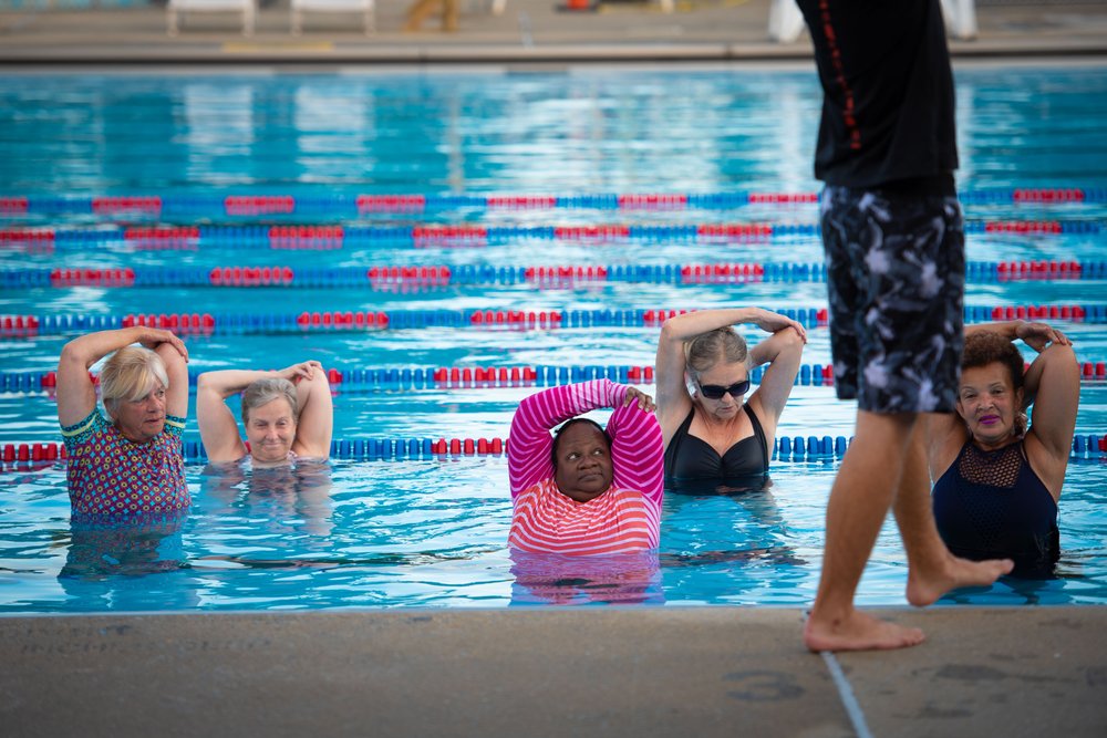Adults stretch in an indoor pool.