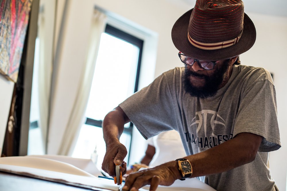 4298c58d0083017wirejohn-jpg.jpeg Wire John cuts out patterns from a bolt of fabric in preparation for Pagwah's "Kritical Mas" J'Ouvert gathering.<br/>