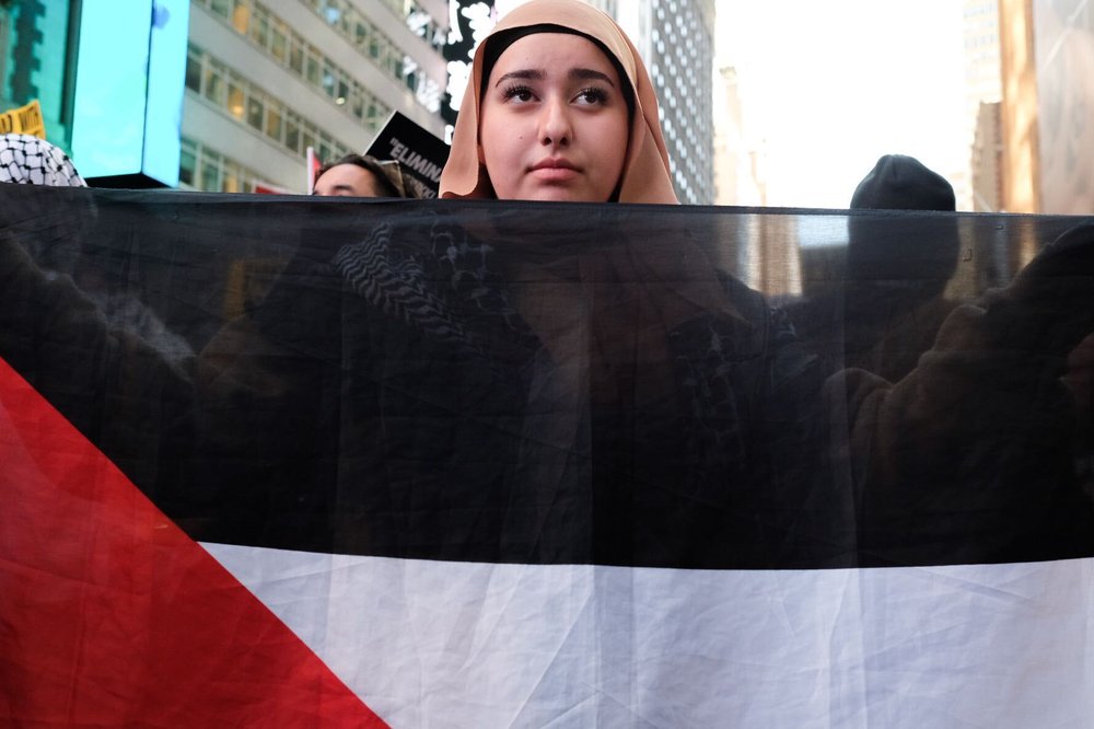 A young woman holds a Palestinian flag at a protest in Times Square.