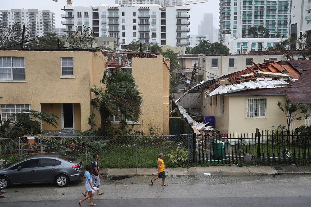 465633b82gettyimages-845380138-jpg.jpeg People walk past a building where the roof was blown off by Hurricane Irma on September 10, 2017 in Miami, Florida. (Getty)