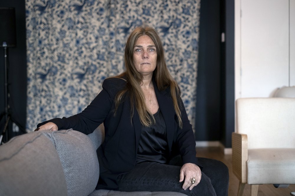 A woman poses for a photo, seated on a couch.