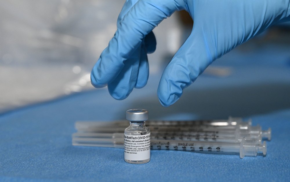 A gloved hand reaches for the COVID-19 vaccine vial with needles in the background. A worker prepare vaccines at Stony Brook University on January 18, 2021