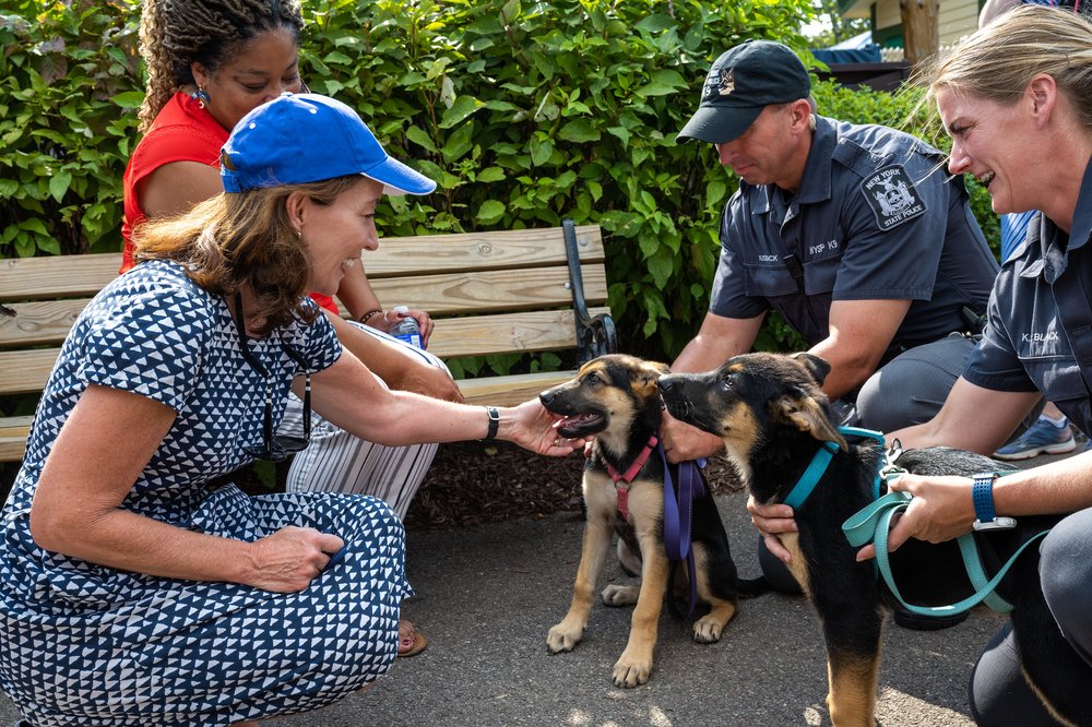 New York Governor Kathy Hochul greets two puppies being trained by the NYS police.