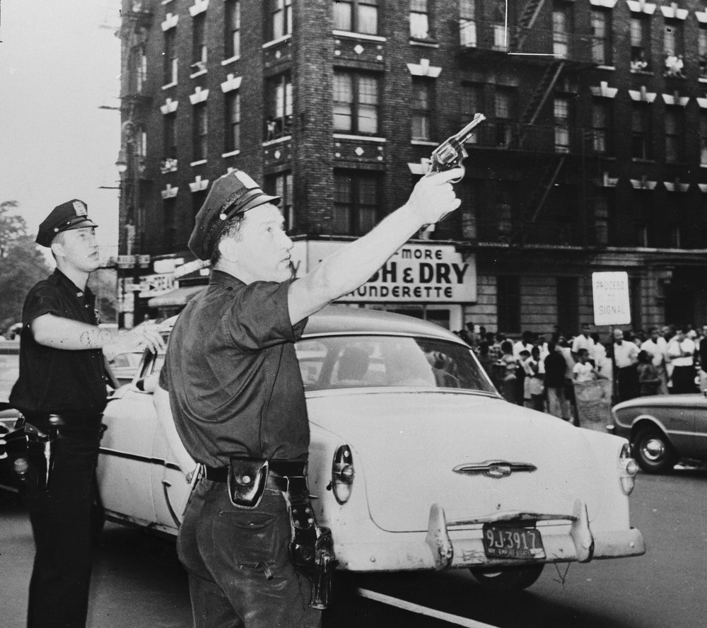 51560be98.jpeg "Two policemen pursue the members of a New York street gang after a fight broke out. November 1961."
