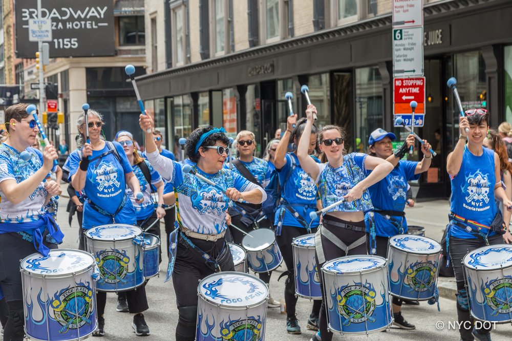A group of women playing drums on an open street