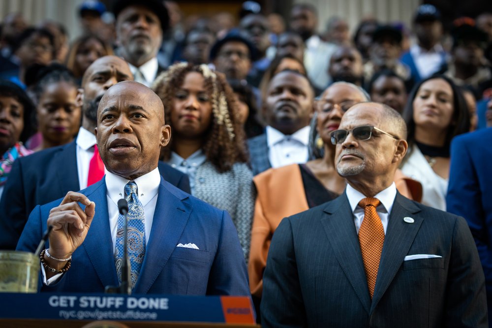 Mayor Eric Adams and Schools Chancellor David Banks speak with a crowd standing behind them.