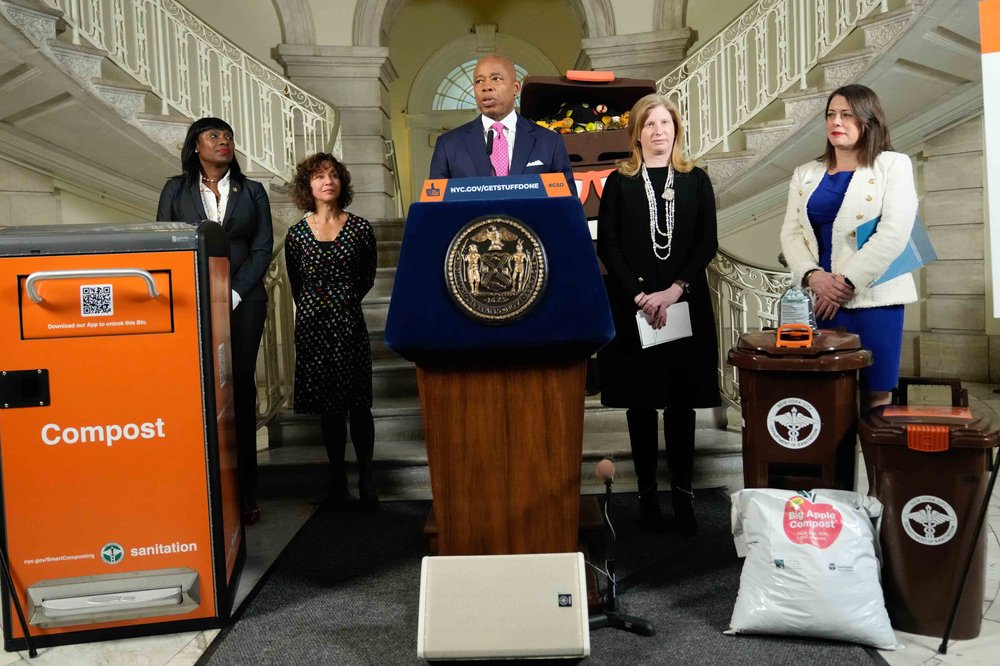 Mayor Eric Adams speaks at a press conference surrounding by composting paraphernalia.