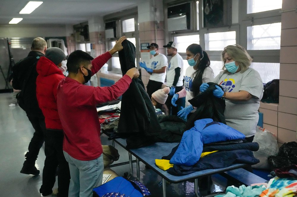 Volunteers sort clothes at a table in a school building.