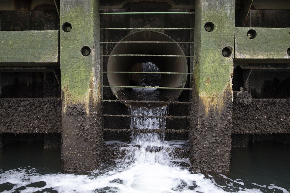 Water flows from a large corroded pipe.