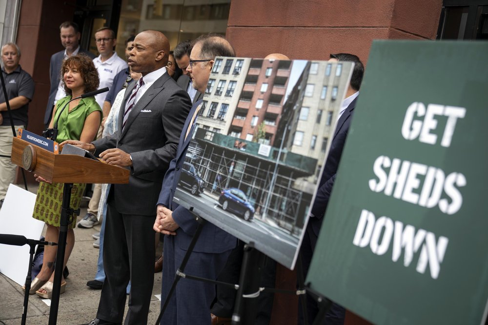 Mayor Eric Adams, Manhattan Borough President Mark Levine and Deputy Mayor for Operations Meera Joshi at a press conference by a sign reading "get signs down."