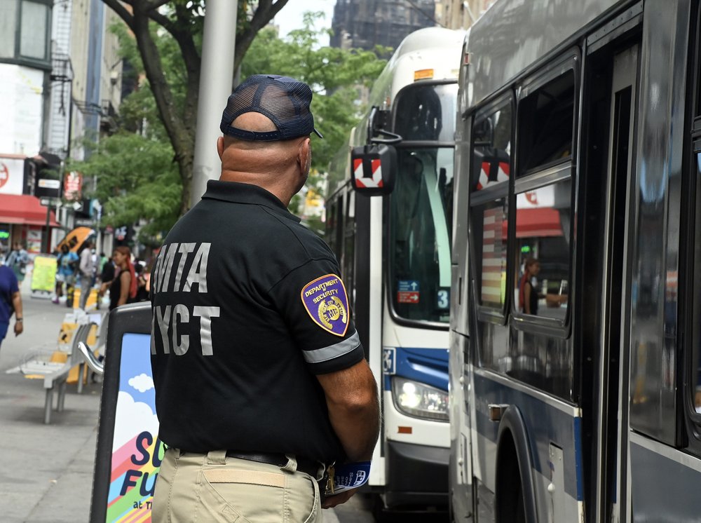 An MTA EAGLE team member watches over a row of buses, looking out for anyone trying to score a free ride.