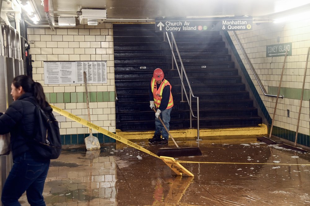 A worker cleans the entrance to a subway station.