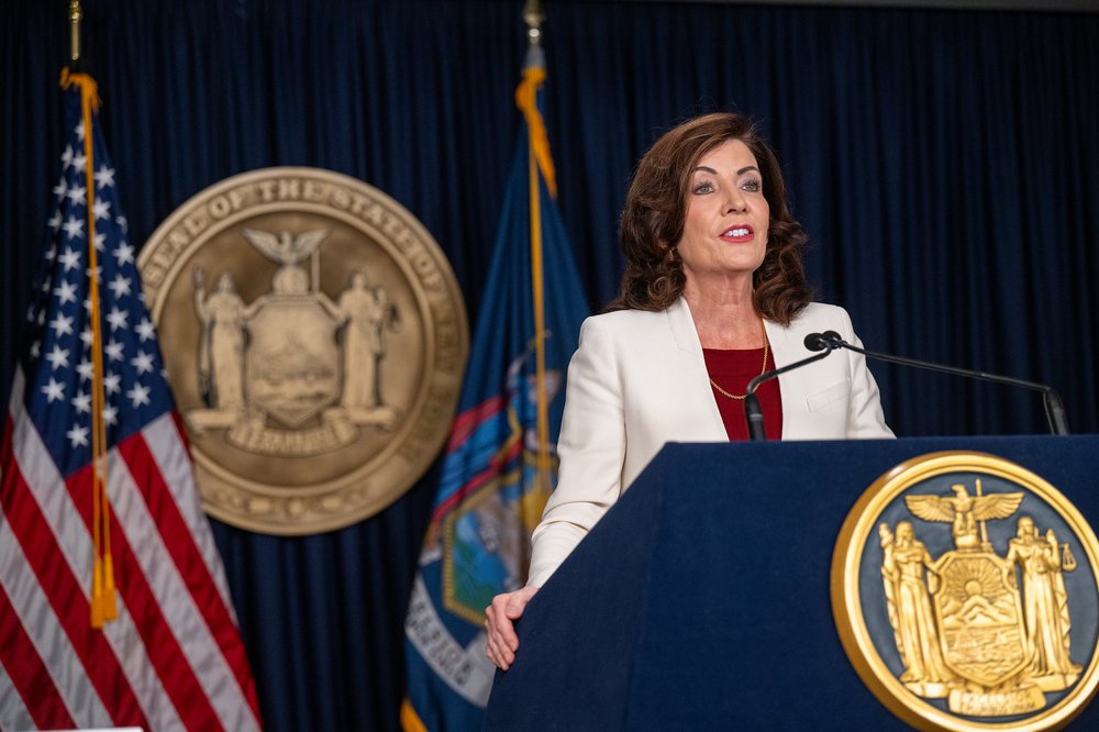 Gov. Kathy Hochul stands behind a navy blue podium with the state seal