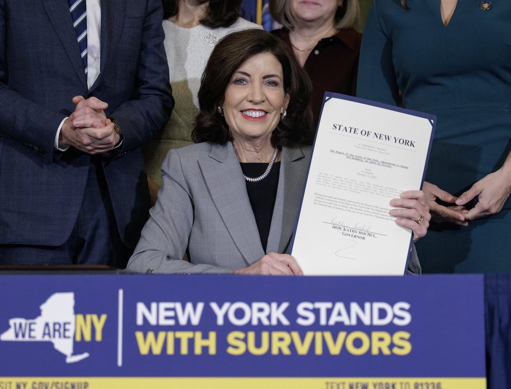 Gov. Kathy Hochul holds up a signed law.