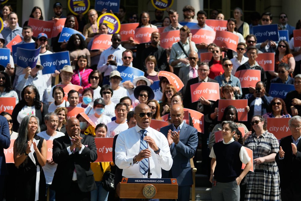 Mayor Eric Adams stands in front of a crowd